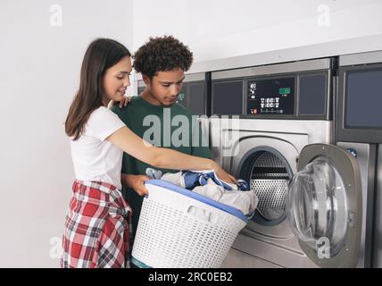 Jeune homme et femme pliant la lessive faisant des corvées à Laundrette Banque D'Images