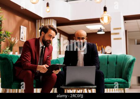 La réception de l'hôtel accueille un voyage d'affaires, représentant le point de départ d'un partenariat dynamique. Deux professionnels de l'entreprise échangent des idées et explorent de nouvelles opportunités qui s'offrent à eux. Banque D'Images