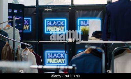 Magasin de détail Black friday avec offres, ventes saisonnières de novembre dans le centre commercial. Vêtements à petits prix dans la boutique de mode, bannières au néon avec promo spéciale pour attirer les clients. Banque D'Images