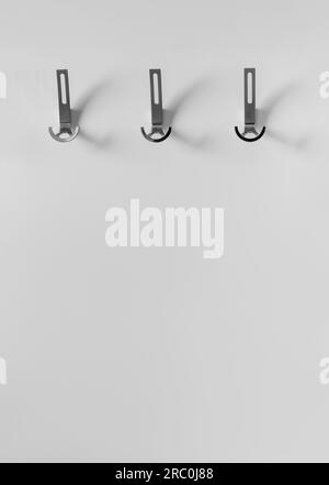 Cintre pour vêtements d'extérieur avec crochets en métal sur un mur blanc dans un intérieur moderne du couloir d'un appartement, maison. Éléments d'intérieur, design de prem Banque D'Images