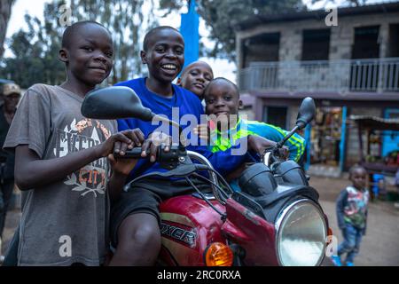 Les enfants aiment jouer sur une moto abandonnée en dehors des rues du bidonville de Kibera à Nairobi. La vie quotidienne à travers les rues de la ville de Nairobi bien connue comme une ville sous le soleil privée du mot Maasaï Enkare qui se traduit par «lieu des eaux fraîches». Nairobi est la plus grande et capitale du Kenya. Banque D'Images