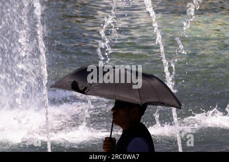 Washington, États-Unis. 11 juillet 2023. Un homme se réfugie du soleil sous un parapluie à Washington, DC, aux États-Unis, le 11 juillet 2023. Crédit : Aaron Schwartz/Xinhua/Alamy Live News Banque D'Images