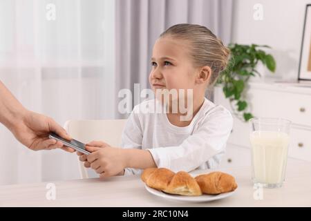 Femme enlevant smartphone de sa fille à la maison, gros plan. Addiction à Internet Banque D'Images
