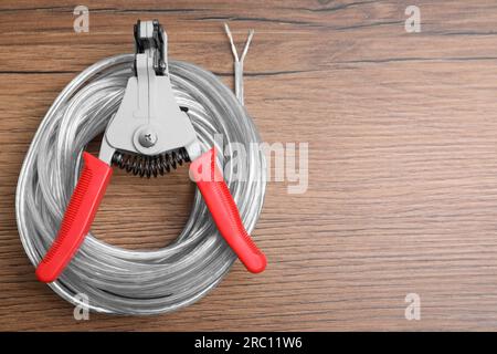 Pinces coupantes et câble avec fil dénudé sur table en bois, vue de dessus. Espace pour le texte Banque D'Images