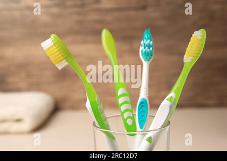 Nouvelles brosses à dents dans le support en verre sur fond flou, gros plan Banque D'Images