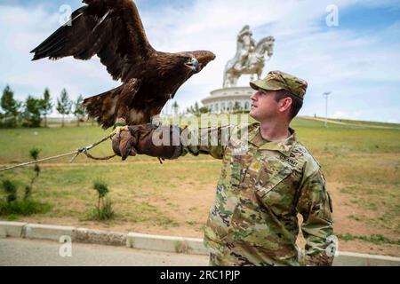 23 juin 2023 - Tsonjin Boldog, Oulan-Bator, Mongolie - le coordinateur du programme de partenariat de l'État de la Garde nationale de l'Alaska, le major Levi Vail pose avec un aigle sur son bras alors qu'il se tient devant la statue équestre de Chinggis Khaan au complexe de statues de Chinggis Khaan sur la rive de la rivière Tuul à Tsonjin Boldog à l'est du Capitale mongole Oulan-Bator, 23 juin 2023. L'Alaska et la Mongolie ont été partenaires en 2003 dans le cadre du Programme de partenariat d'État de la Garde nationale. Plus de 1 500 gardes de l'Air et de l'Armée de terre de l'Alaska se sont rendus en Mongolie pour des entraînements et des exercices à l'appui de la paix mongole Banque D'Images