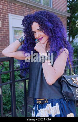 Une femme de cinquante ans qui a l'air jeune avec de longs cheveux bouclés violets et une tenue d'été à Greenwich Village, New York City Banque D'Images