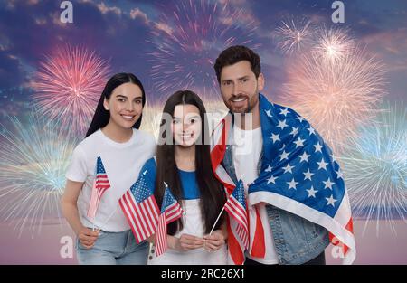 4 juillet - jour de l'indépendance de l'Amérique. Famille heureuse avec drapeaux nationaux des États-Unis contre ciel avec feux d'artifice Banque D'Images