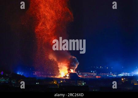 Les gens regardent l'incendie du feu de joie loyaliste de Craigyhill à Larne, Co Antrim, la onzième nuit. Inaugurant les douzième commémorations. Date de la photo : mercredi 12 juillet 2023. Banque D'Images