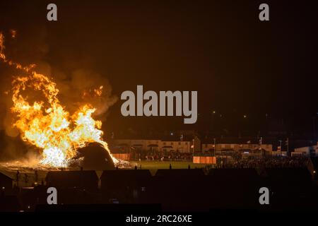 Les gens regardent l'incendie du feu de joie loyaliste de Craigyhill à Larne, Co Antrim, la onzième nuit. Inaugurant les douzième commémorations. Date de la photo : mercredi 12 juillet 2023. Banque D'Images