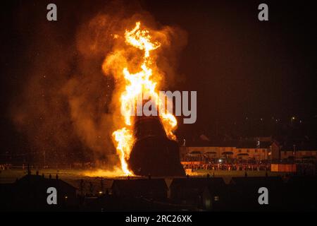 Les gens regardent l'incendie du feu de joie loyaliste de Craigyhill à Larne, Co Antrim, la onzième nuit. Inaugurant les douzième commémorations. Date de la photo : mercredi 12 juillet 2023. Banque D'Images