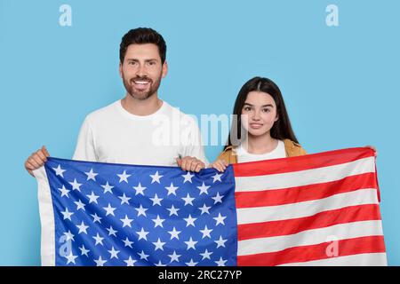 4 juillet - jour de l'indépendance des États-Unis. Homme heureux et sa fille avec drapeau américain sur fond bleu clair Banque D'Images