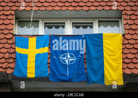 Drapeaux de l'OTAN, de la Suède et de l'Ukraine brandissant sur la fenêtre lors du sommet de l'OTAN 2023 dans le centre de Vilnius, en Europe Banque D'Images