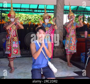 Un jeune homme prie devant des danseuses en costumes traditionnels au sanctuaire d'Erawan, un sanctuaire hindou à l'intersection Ratchaprasong sur Ratchadamri Road dans le sous-district de Lumphini, Bangkok, Thaïlande Banque D'Images