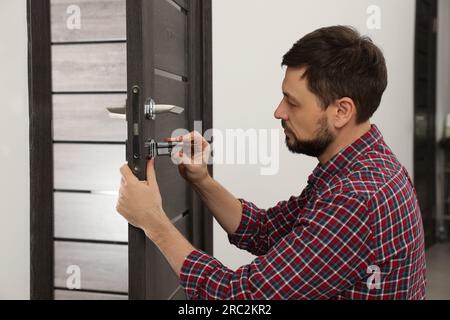 Bricoleur changeant le noyau de serrure de porte à l'intérieur Banque D'Images