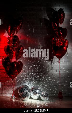 Beaucoup de boules disco brillantes dans la chambre décorées avec des ballons en forme de coeur, de couleur tonique Banque D'Images