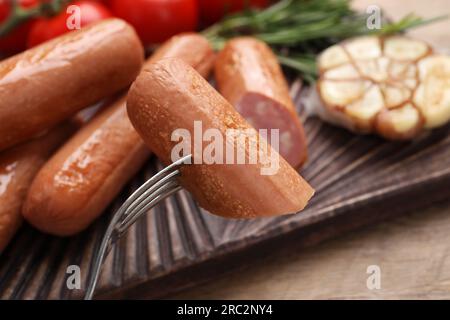 Délicieuse saucisse végétalienne sur la fourchette au-dessus de la table en bois, gros plan Banque D'Images