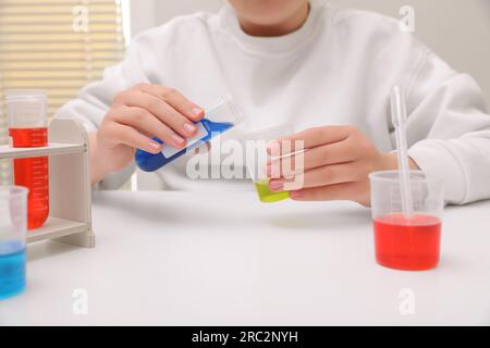 Fille mélangeant des liquides colorés à la table blanche à l'intérieur, gros plan. Kit d'expérimentation chimique pour enfants Banque D'Images