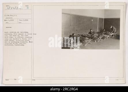 Cette photographie représente le lieutenant Wm. Fox of base Hospital No.29 le 1 mars 1919, dans un service à Rico rempli de patients atteints de grippe. L'image montre les patients couchés dans des directions alternées, avec une tête vers le haut et l'autre tête vers le bas, dans une tentative d'empêcher la toux dans le visage de l'autre. Toutes les personnes présentes dans le service, y compris l'infirmière, peuvent être vues portant des masques. Banque D'Images