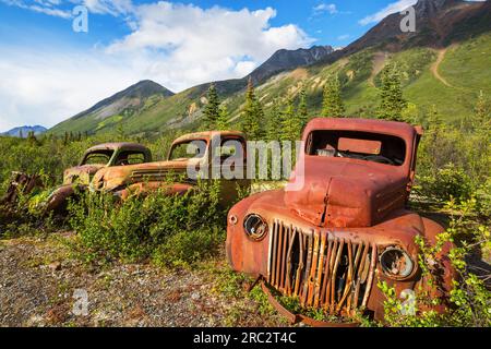 Une gamme de camions rouillés abandonnés après la guerre qui rouillent dans le désert pendant l'été dans le nord du Canada Banque D'Images