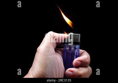 Allumez un briquet à essence sur fond noir Banque D'Images