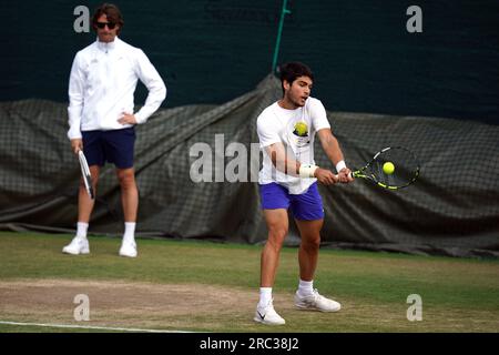 Carlos Alcaraz en action sur les terrains d'entraînement, sous l'œil vigilant de son entraîneur Juan Carlos Ferrero (à gauche) lors de la dixième journée des Championnats de Wimbledon 2023 au All England Lawn tennis and Croquet Club à Wimbledon. Date de la photo : mercredi 12 juillet 2023. Banque D'Images