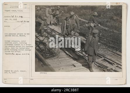 Des prisonniers allemands, escortés par des soldats américains, transportent un camarade blessé à travers un pont jusqu'à un vestiaire à Boureuilles, en France. La photographie, prise le 26 septembre 1918, montre l'avancée américaine dans la région de l'Argonne pendant la première Guerre mondiale Notez le fil barbelé précédemment placé sur le pont.' Banque D'Images