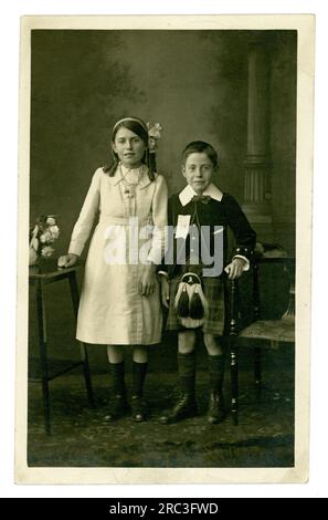 Originale charmante carte postale du début des années 1900 de 2 jeunes enfants écossais édouardiens attrayants, frère et sœur dans leurs vêtements intelligents, le garçon est habillé dans un kilt écossais, pour un jour spécial du drapeau, vers 1910. Musselburgh, East Lothian, Écosse, sur la côte du Firth of Forth, Royaume-Uni Banque D'Images