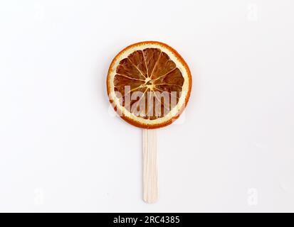 Tranches d'orange avec bâton de crème glacée isolé sur fond blanc. Image conceptuelle de bonbons sucette ou de crème glacée Banque D'Images