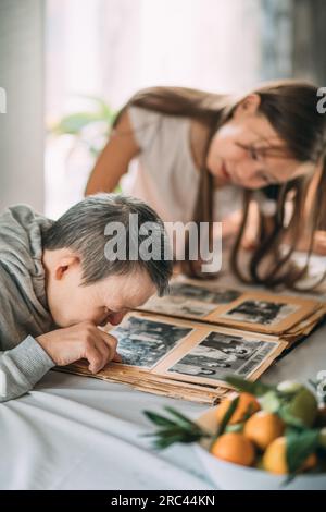 Exploring Memories : a Journey Through an Old Family Album avec photos en noir et blanc d'une jeune fille et d'une femme âgée souffrant du syndrome de Down Banque D'Images