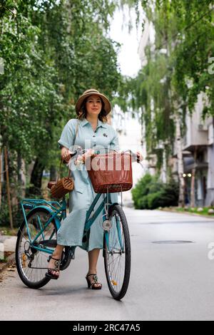 une jeune belle femme roule un vélo dans une rue verte d'été Banque D'Images