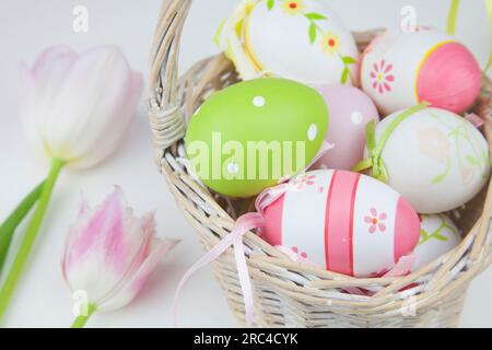 Photo studio d'oeufs de Pâques décorés dans un panier en osier. Fêtes religieuses Banque D'Images