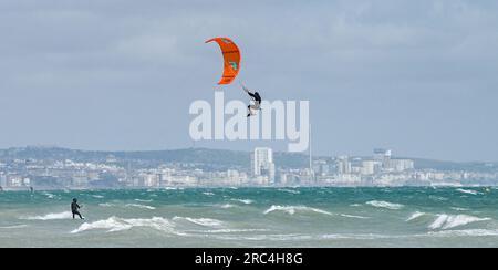 Brighton Royaume-Uni 12 juillet 2023 - les kitesurfers profitent des conditions aérées au large de la plage de Lancing, près de Brighton, que l'on peut voir au loin alors que le temps instable devrait se répandre à travers la Grande-Bretagne dans les prochains jours : Credit Simon Dack / Alamy Live News Banque D'Images