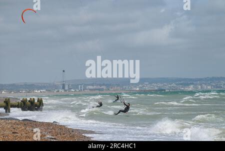 Brighton Royaume-Uni 12 juillet 2023 - les kitesurfers profitent des conditions aérées au large de la plage de Lancing, près de Brighton, que l'on peut voir au loin alors que le temps instable devrait se répandre à travers la Grande-Bretagne dans les prochains jours : Credit Simon Dack / Alamy Live News Banque D'Images