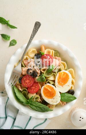 Salade de pâtes italiennes. Pâtes orecchiette au thon, à la tomate cerise, à l'olive, au basilic et au parmesan dans une assiette sur fond de pierre grise ou de béton. TRADI Banque D'Images