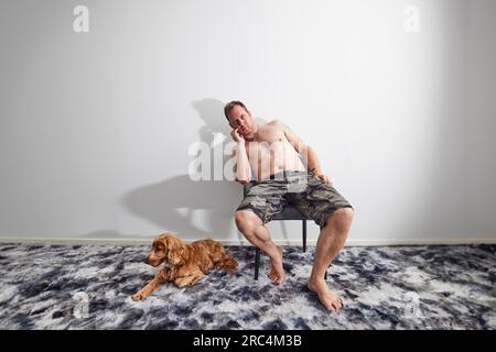 Homme assis sur une chaise avec cocker spaniel en été Banque D'Images