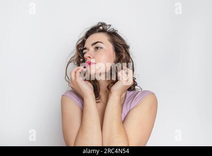 Femme pensive avec la main près du visage. Cheveux ondulés foncés, sourcils noirs, gros yeux bruns Banque D'Images