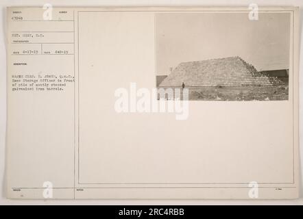 Le Major Charles E. Jones se tient en tant qu'agent de stockage de zone devant une pile méticuleusement arrangée de barils en fer galvanisé. Cette photographie a été prise le 17 avril 1919 par le sergent Gray du corps d'approvisionnement. L'image illustre la nature organisée des activités de stockage militaire pendant la première Guerre mondiale. Banque D'Images