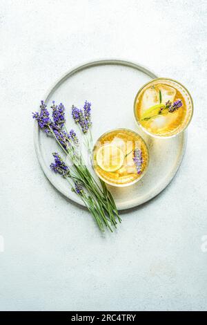 Vue de dessus du cocktail d'été avec vodka et lavandula servi dans des verres avec glace et tranche de citron vert sur plaque blanche sur fond flou Banque D'Images