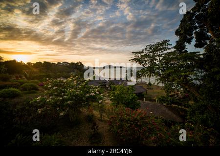 Vue panoramique des arbres verdoyants poussant sur la rive de l'océan calme avec bungalows de l'hôtel à Madagascar sous ciel nuageux Banque D'Images