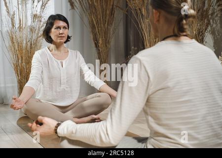 Mari et femme se relaxant dans Padmasana yoga pose avec les mains dans Gyan mudra tout en faisant des exercices de respiration de yoga près des planches de sadhu Banque D'Images