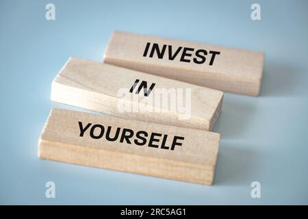 Investissez en vous-même, les blocs de bois forment un slogan, investissez en vous-même, le concept de développement et de réalisation de soi dans la vie et les affaires, belle l Banque D'Images