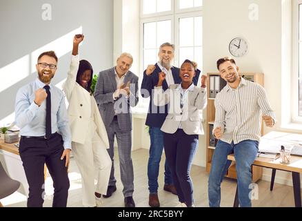 Heureux collègues d'affaires multi-ethniques célébrant le succès dans le bureau Banque D'Images