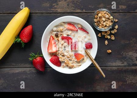 Bol granola avec lait alternatif et fraises. Vue de dessus de la table. Concept d'alimentation propre, régime Banque D'Images