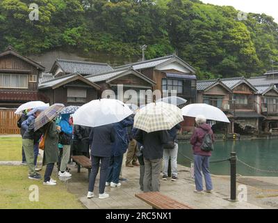 Groupe de touristes abri sous leurs parapluies lors d'une visite d'une journée humide au pittoresque village de pêcheurs d'INE dans la préfecture de Kyoto, au Japon. Banque D'Images