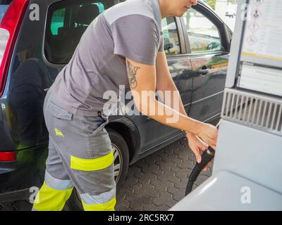 Cremona, Italie - juillet 3 2023 Femme de service caucasienne à la station-service de la ville d'Eni Agip pompant de l'essence à une voiture de client Banque D'Images
