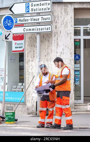 Ouvriers du conseil regardant les instructions pour peindre les marquages des passages piétons dans le centre-ville - Tours, Indre-et-Loire (37), France. Banque D'Images