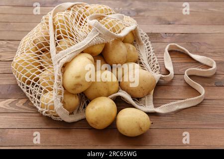 Sac de ficelle avec des pommes de terre crues sur fond en bois Banque D'Images