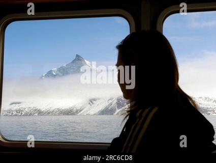 Une femme regarde par la fenêtre le paysage glacé lors d'une visite des cours d'eau à l'extérieur de Nuuk, au Groenland Banque D'Images