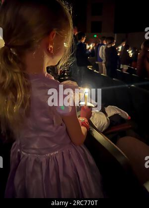 Fille caucasienne en robe pendant un service religieux à la lumière des bougies. Banque D'Images